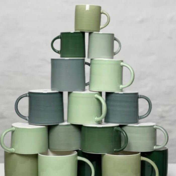 Stack of Anne Black hand-glazed ceramic mugs in various shades of green
