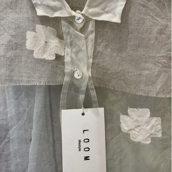 Close-up of LOOM Lifestyle white silk shirt with sheer floral applique detail and mother-of-pearl buttons