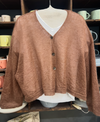 Brown cardigan on a mannequin with a blurred background of shelves with cups.