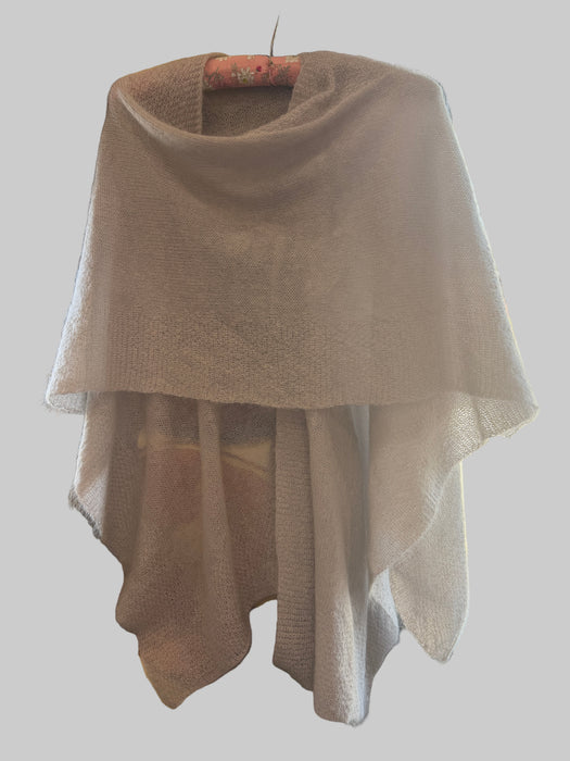Beige sweater draped over a chair with a blurred indoor background
