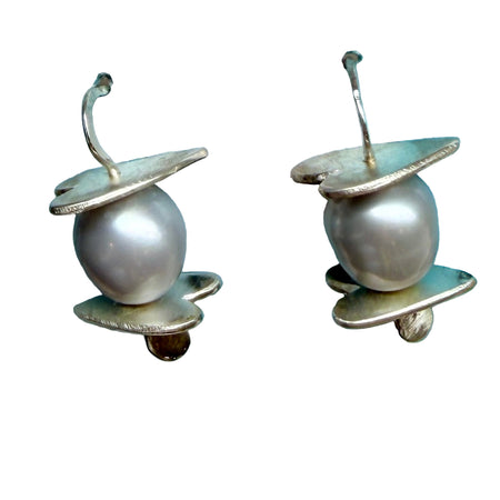 Pair of pearl earrings on a blue decorative surface