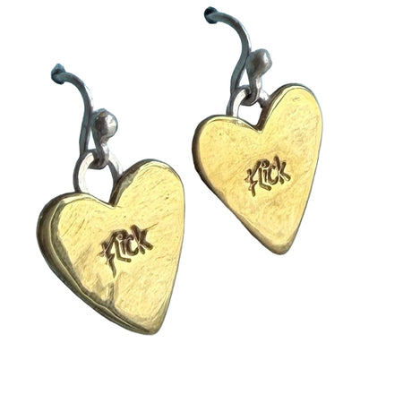 Gold heart-shaped earrings with 'Luck' engraving on a blue textured surface
