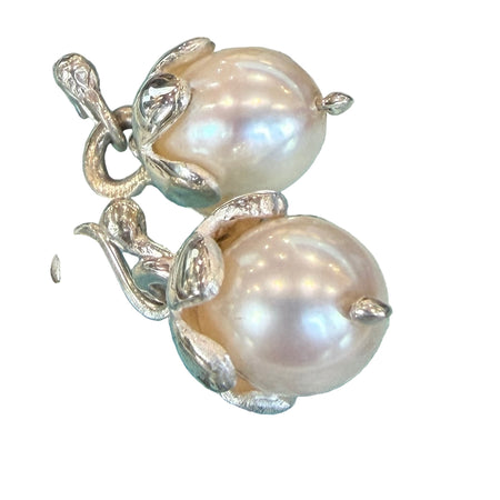 Pearl earring with silver setting on a decorative fabric background