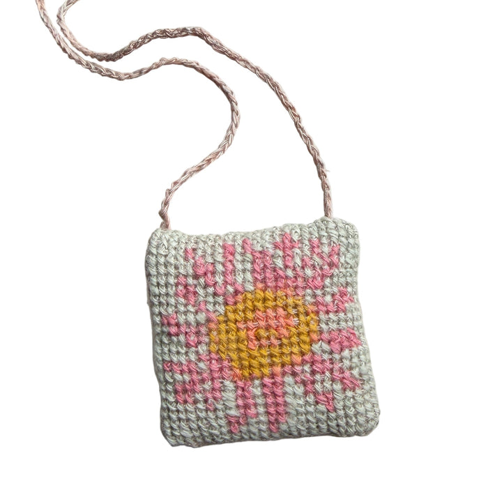 Small embroidered box with a floral design on a textured white surface