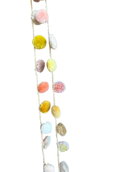 String of multicolored pom-poms on a wooden surface
