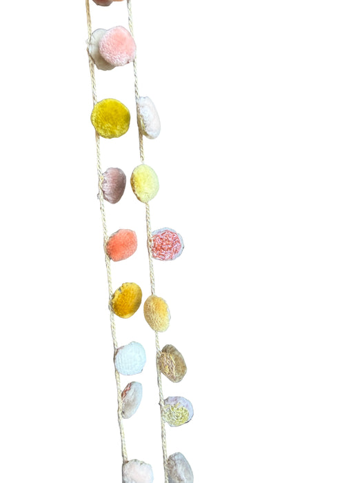 String of multicolored pom-poms on a wooden surface