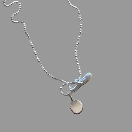 Silver necklace with a pendant on a wooden surface