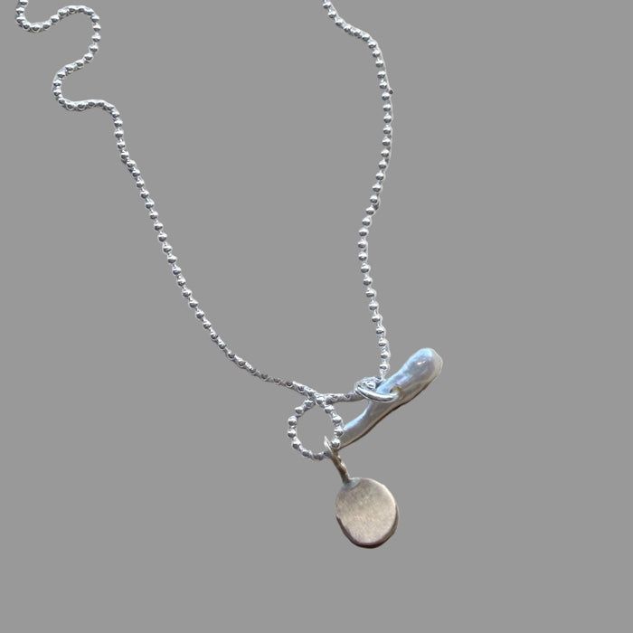 Silver necklace with a pendant on a wooden surface