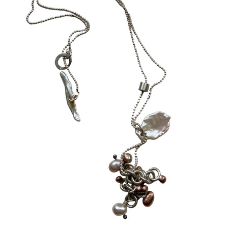 Silver necklace with various charms on a light gray background