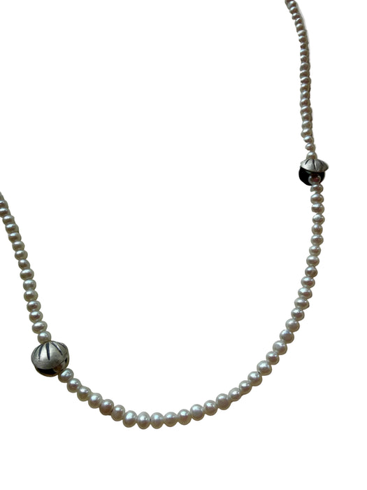 Pearl necklace with silver beads on a light gray background