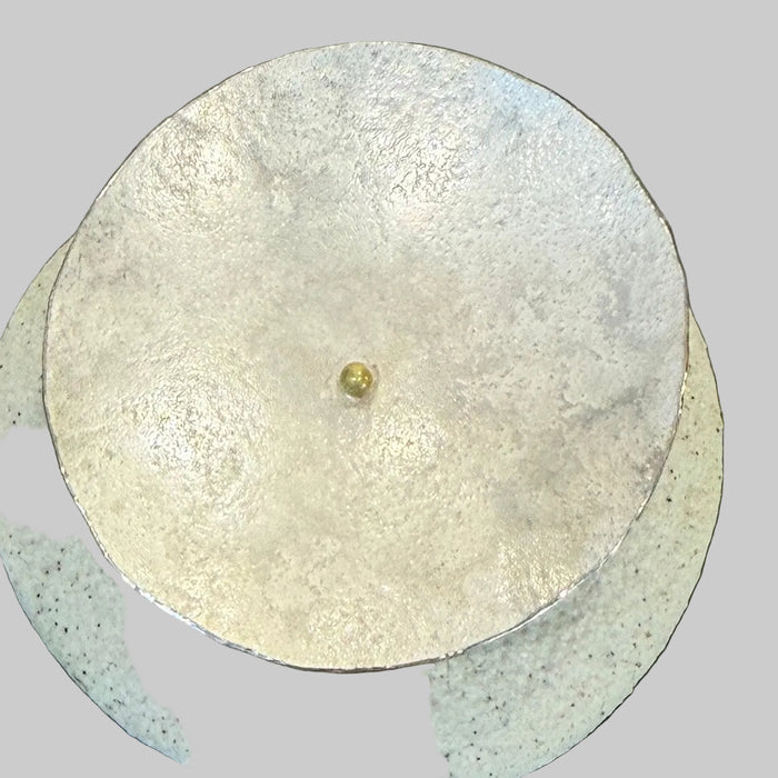 Small gold object on a round metallic surface with a dark background