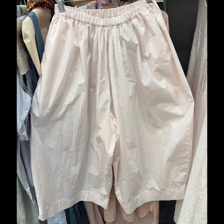 Light pink shorts on a rack with other clothing items.