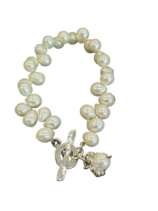 Pearl bracelet with silver charms on a dark background