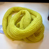 Yellow knitted scarf on a white surface