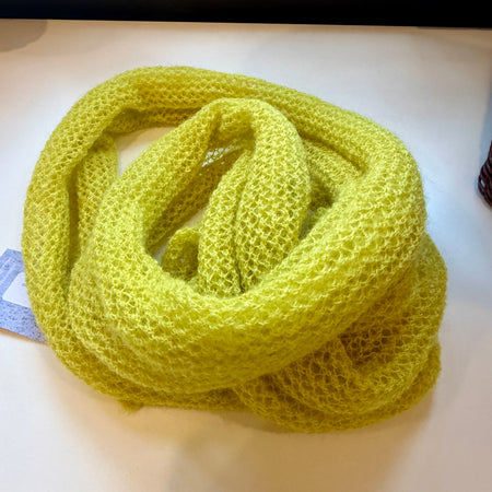 Yellow knitted scarf on a white surface