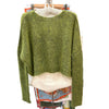 Green sweater on a hanger with a blurred background of clothing racks.