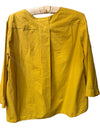 A mustard yellow long-sleeve linen blouse hanging on a wooden hanger against a rustic wooden ladder background.