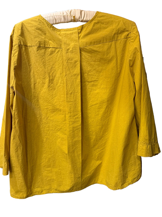 A mustard yellow long-sleeve linen blouse hanging on a wooden hanger against a rustic wooden ladder background.