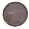 A round, shallow ceramic dish in a dusty mauve-brown glaze, featuring the name 'Jade' written in white script in the center, set against a light sage green background.