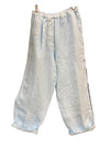 Light blue wide-leg cropped pants with an elastic waistband, hanging in front of a wooden shoe display case.