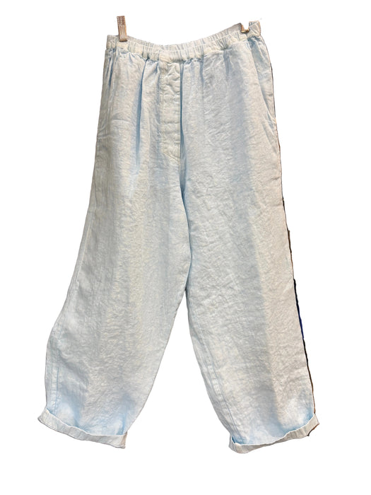 Light blue wide-leg cropped pants with an elastic waistband, hanging in front of a wooden shoe display case.