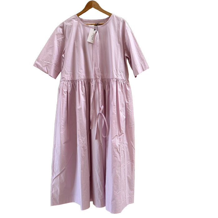 A light pink short-sleeve dress with a gathered waist and drawstring, hanging on a wooden hanger against a light wood panel background.