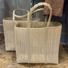 Two woven baskets with handles on a concrete surface.