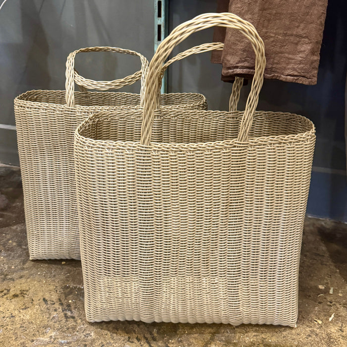 Two woven baskets with handles on a concrete surface.