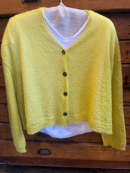 Yellow cardigan on a mannequin against a wooden background