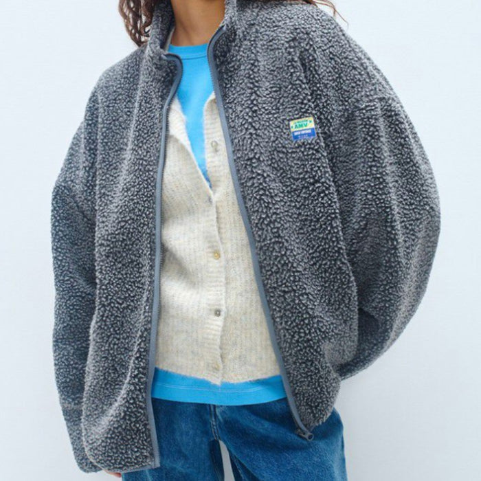 Model wearing an American Vintage charcoal grey sherpa fleece zip jacket open over a cream cardigan, blue tee and jeans
