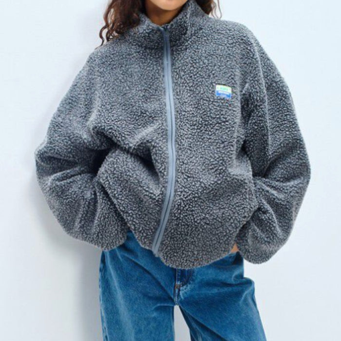 Model wearing the American Vintage charcoal grey sherpa fleece jacket zipped to the collar, hands in pockets, with blue jeans