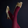 Detail of Tightology claret Aran cashmere blend tights showing cable knit pattern, with cream and gold heels