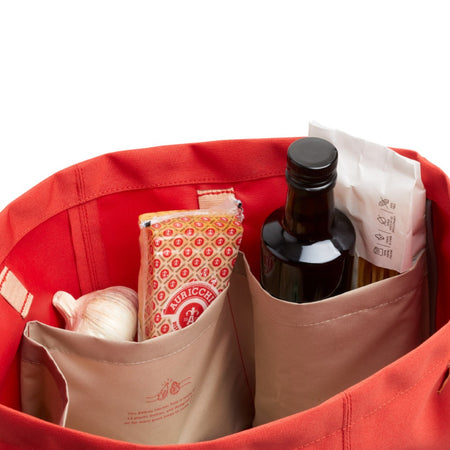 Inside the Bellroy Market Tote in red, showing internal pockets that hold bottles upright and keep groceries separated