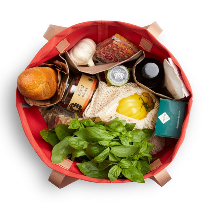 Bellroy Market Tote in red, a large shopping tote bag packed with groceries and fresh produce, top view