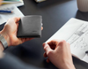 Bellroy Note Sleeve leather wallet in black, held in hand at a desk
