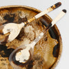 Dinosaur Designs long Stone resin salad servers resting in a swirled amber resin salad bowl
