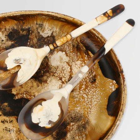 Dinosaur Designs long Stone resin salad servers resting in a swirled amber resin salad bowl