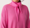 Person wearing a pink sweater with a matching pink scarf on a white background