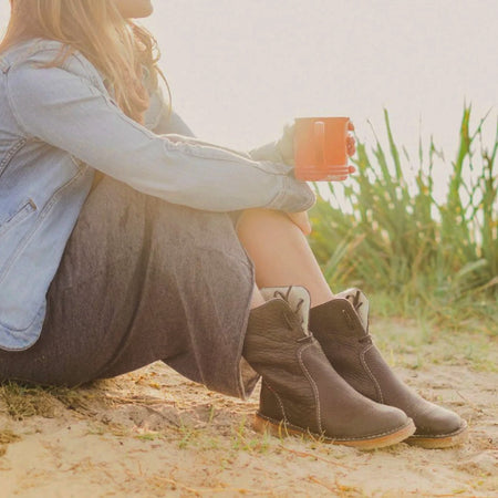 Woman wearing Duckfeet Arhus shearling lined boots with a knit skirt, sitting outdoors