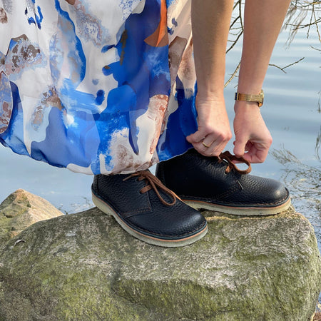 Woman wearing Duckfeet Helsingør black pebbled leather lace-up boots on a rock outdoors