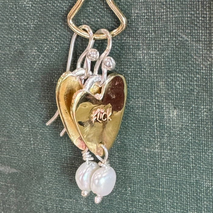 Close-up of a Flick Pope brass heart earring with a white pearl drop