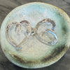 Flick Pope Cross Your Heart silver studs from above, on a ceramic dish