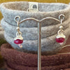 Flick Pope pomegranate puff earrings displayed on a felt bowl in store