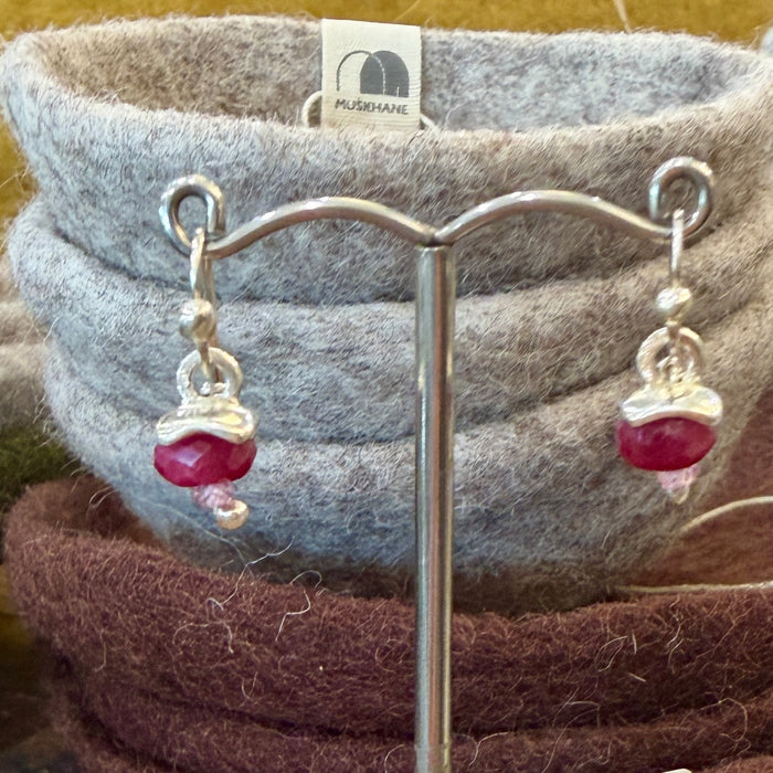 Flick Pope pomegranate puff earrings displayed on a felt bowl in store