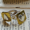 Flick Pope signet heart rings in brass and silver on a book page