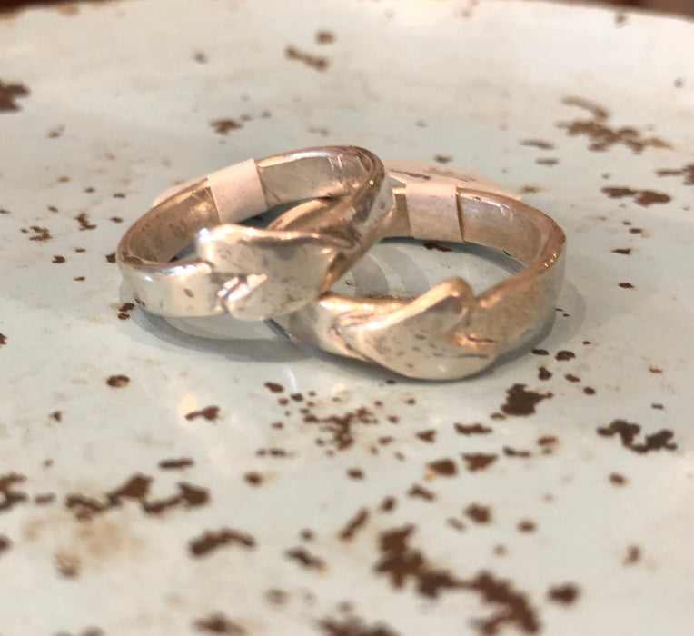 Two Flick Pope heart on side rings on a speckled surface