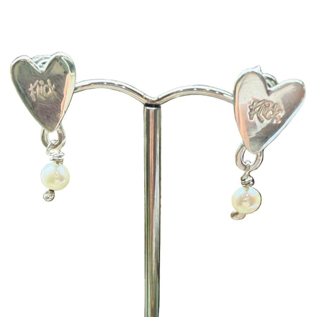 Flick Pope silver heart stud earrings with white pearl drops, on a stand