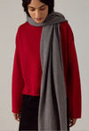 Francie Cloud possum merino scarf in granite grey, held draped over a red jumper