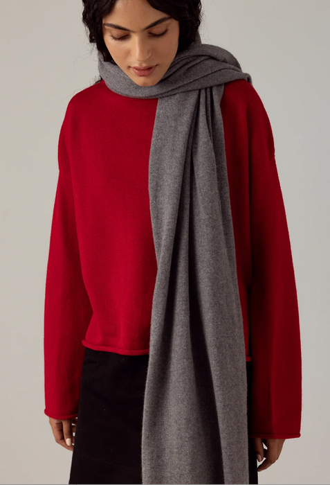 Francie Cloud possum merino scarf in granite grey, held draped over a red jumper