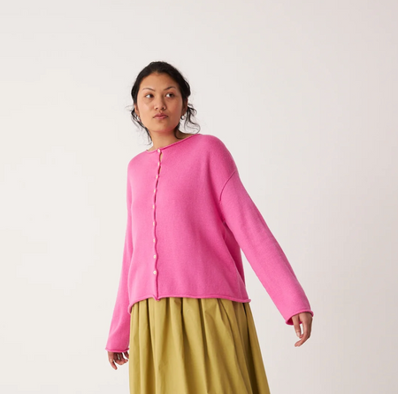 Person wearing a pink cardigan over a yellow skirt on a white background